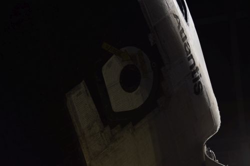 Space Shuttle Atlantis crew cabin and hatch, against an inky background.